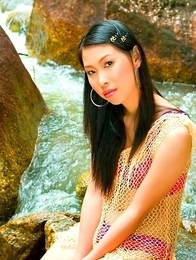 Olive Moon stands in her pink bra and she takes off her scarf. She sits down on a rock and feels on her hot body.