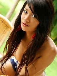 Lovely Benz Sarawadee is having an outdoor shooting and she is sitting on the wooden chair.